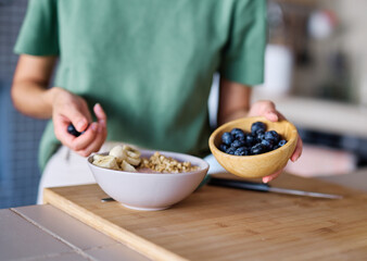 Portrait of a young woman preparing and eating breakfast, drinking juice in the kitchen at home