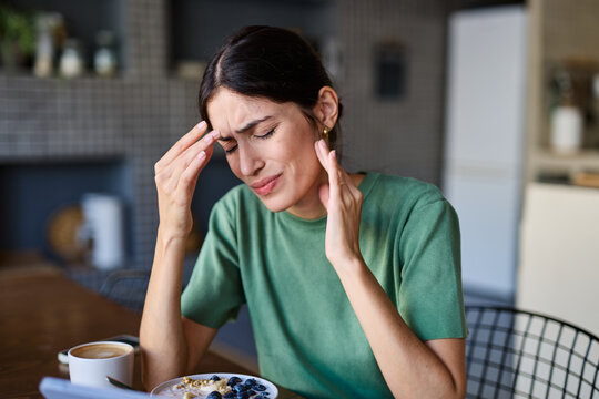 Portrait of a young woman with laptop or tablet with a headache  frustrated, stress anxiety problem concepts at home
