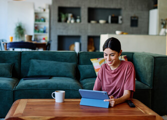Portrait of a young woman  using tablet or laptop computer, having online meeting or browsing...