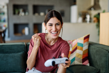 Portret of a young latina woman having fun playing video game on console computer with joystick  at...
