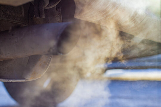 Close-up of car smoking exhaust pipe, car with gasoline engine. Gasoline engine warming up at idle in winter season. Blue exhaust smoke