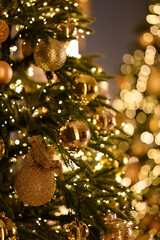 Close-up of a beautifully decorated Christmas tree with golden ornaments, sparkling lights, and festive bokeh in the background.