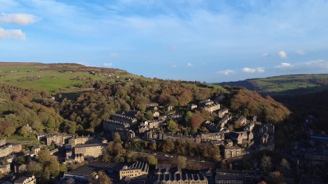 Aerial view of the town of hebden bridge in autumn sunlight showing the streets town surrounded by trees and hills