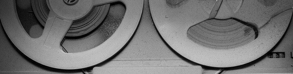 A close-up black and white photograph of an old tape recorder and a player for vinyl records and...