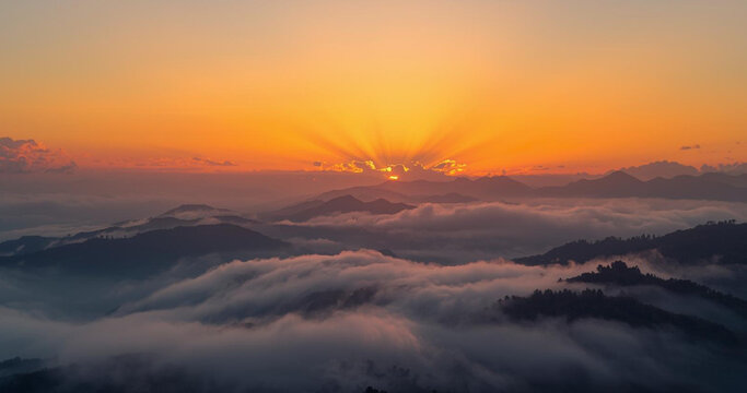 Breathtaking sunrise over majestic mountain range with radiant golden light piercing through the clouds, creating a peaceful, serene landscape scene