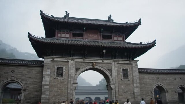 An ancient city gate with a layered roof and red lanterns stands tall in Enshi, China under a cloudy sky, showcasing traditional architecture. 4k video