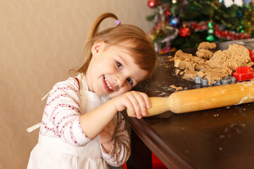 Little girl smiling while baking gingerbread cookies at home