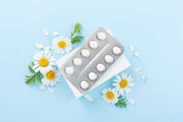 Fresh chamomiles with medicines on color background, top view