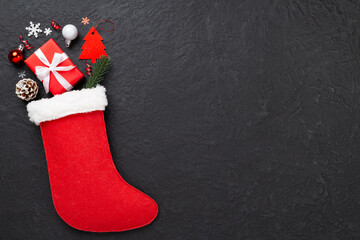 Christmas sock with gifts and decoration on concrete background, top view