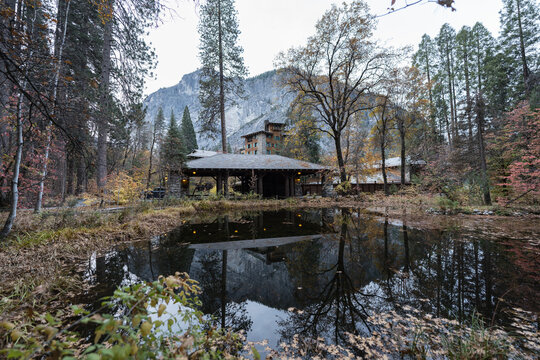 Autumn pond reflecting granite cliffs of Glacier Point and the grand historic hotel in Yosemite National Park.