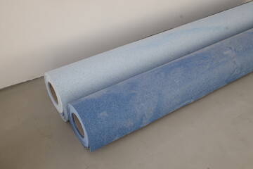 Renovation room with colorful linoleum rolls lying on unfinished concrete floor before installation