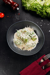 Broccoli in creamy parmesan sauce on dark plate, overhead, restaurant style