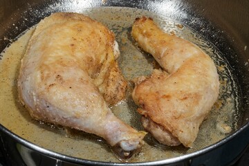 A chicken leg browning in a frying pan