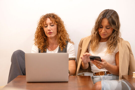 Business women working together using laptop and smartphone