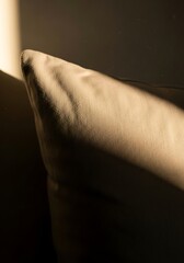 Sunlit cushion texture highlighting fabric details and subtle gradations within a shadowed corner evoking comfort