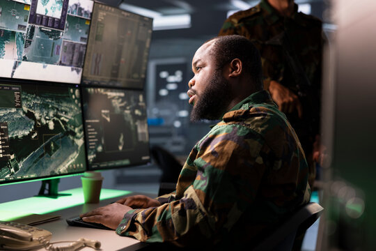 Army operative conducts tactical reconnaissance, utilizing equipment for data analysis and mission planning. Air defense forces agent looks at aerial map on screen, pinpointing targets - Powered by Adobe