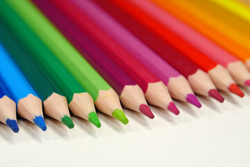 New wooden colored pencils of rainbow colors, perfectly sharpened, lie on table