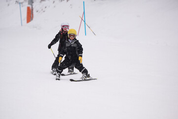 Children learning skiing on snowy mountain slope