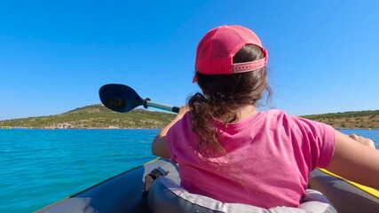 Young girl kayaking in the sea on sunny day. Young female kayaker paddling through serene ocean waters, enjoying sunny summer day with picturesque coastal landscape surrounding her leisure adventure