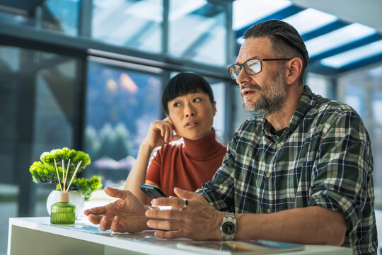 Colleagues having serious conversation in modern office lounge
