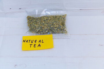 Natural chamomile tea in transparent plastic bag on white background