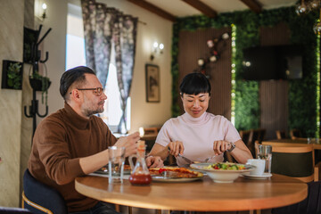 Diverse couple enjoying delicious restaurant lunch during date