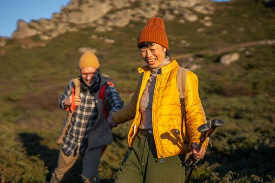 Happy couple holding hands hiking mountain trail
