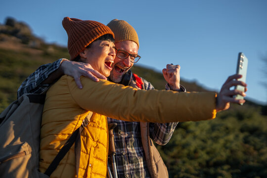 Joyful couple celebrating hiking achievement taking selfie