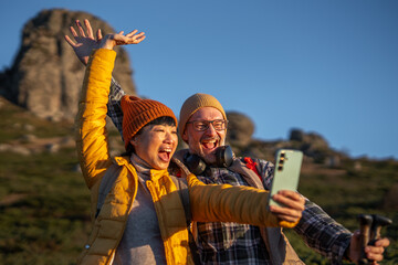 Happy couple enjoying mountain hiking and taking selfie