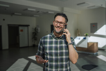 Happy man communicating on phone in office lobby