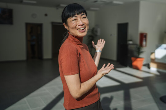 Asian woman smiling and gesturing welcoming presentation