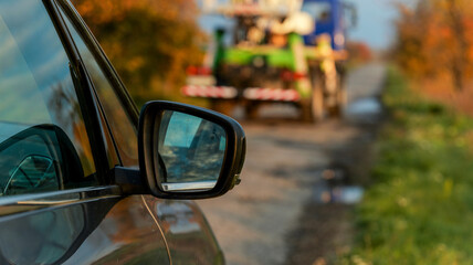 Car side mirror with a truck on a rural road in autumn