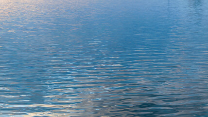 Abstract view of rippling water with reflections of the sky and sunlight