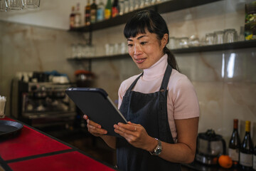 Asian woman waitress smiling using digital tablet in cafe