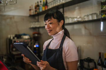 Asian woman waitress smiling using digital tablet in cafe