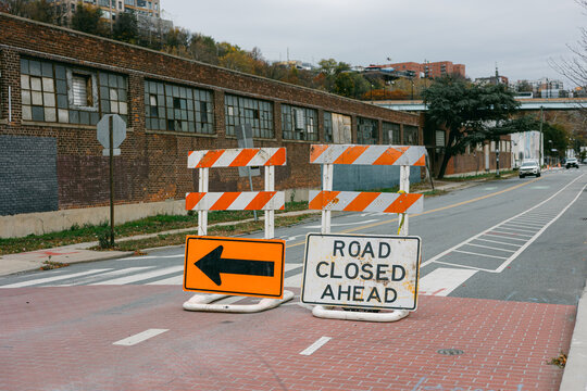 Road closure signs block traffic in urban area on a cloudy day