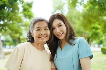 Fototapeta premium Caregiver assisting elderly Asian woman during a walk in the garden.