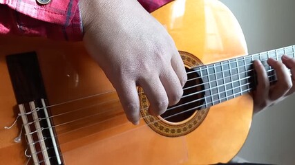 Man strumming fingerstyle acoustic guitar in a sunny day