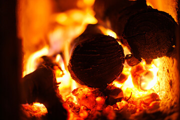 Burning firewood in fireplace. Close-up of burning logs in a fireplace, warm orange flames and glowing embers - cozy heat and winter mood.