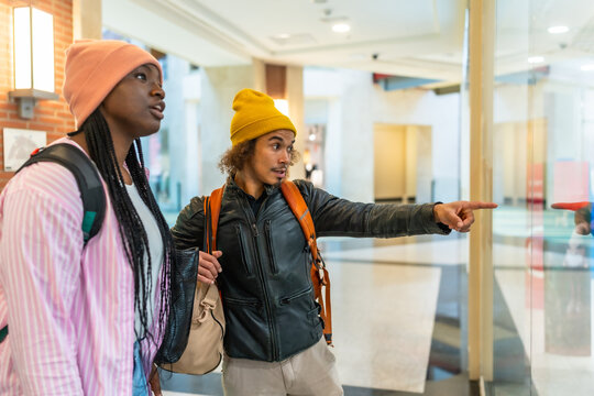 Young friends window shopping at modern mall together