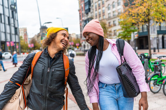 Diverse young couple laughing walking together in city street
