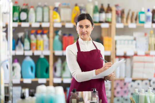 Female worker conducts an inventory to replenish the stock of the warehouse. Saleswoman in the household department of a supermarket checks the remnants of cleaning products