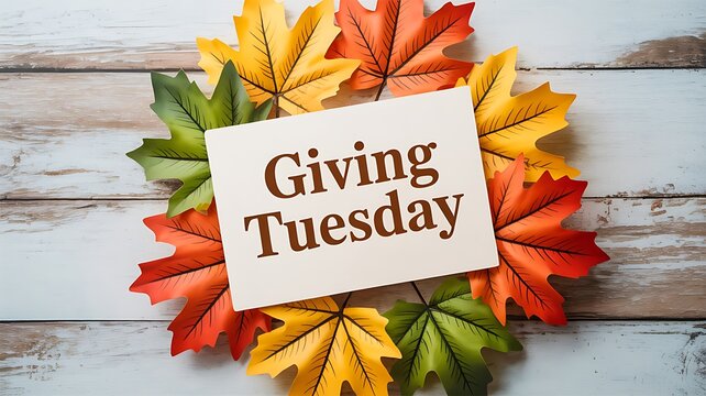 A giving tuesday message surrounded by vibrant fall leaves on a rustic wooden surface, promoting charitable giving and community support during the holiday season