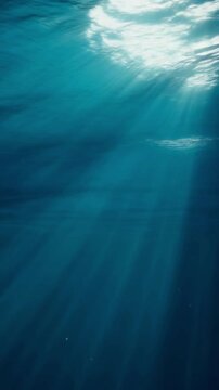Serene deep blue underwater scene with mesmerizing sun rays penetrating the water's surface, creating a tranquil aquatic light effect.