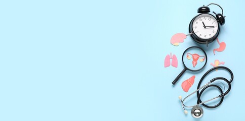 Alarm clock with stethoscope, paper human organs and magnifier on blue background with space for text