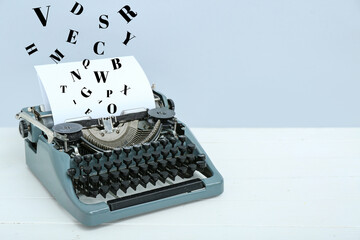 Vintage typewriter on white wooden table near grey wall
