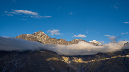 Snow-capped mountain peak with clouds and blue sky in Kazbegi, Georgia, showing stunning natural beauty.