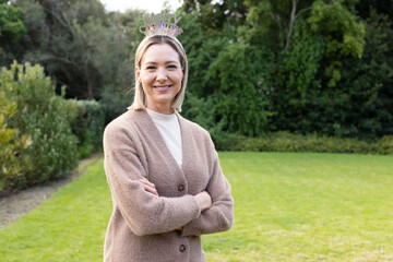 Woman standing on green backyard lawn wearing sparkly Merry Christmas headband and cozy cardigan