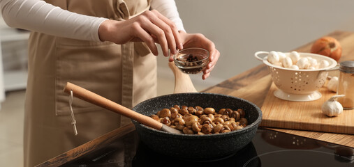 Woman peppering roasted mushrooms in kitchen, closeup