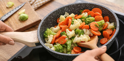 Young woman roasting tasty vegetables in kitchen, closeup